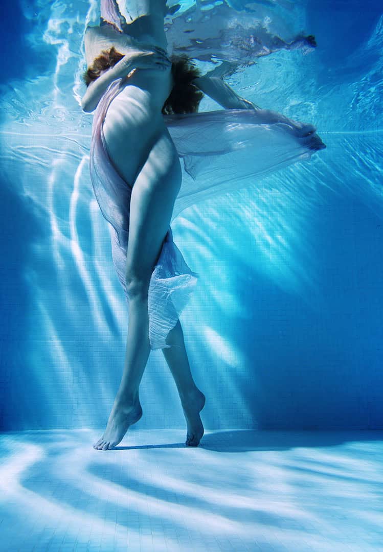 Elegant gravidfotografering under vann, fremhever kvinnens naturlige skjønnhet og graviditetens magi med kreativ bruk av vann og lys. Perfekt for minner av svangerskapet.