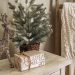 Small artificial Christmas tree on a nightstand beside stacked books labeled with festive holiday terms — minimalist Christmas decor on a budget from By Paige Nicole.