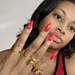 Medium brown woman with long red nails, wearing gold monogram rings