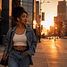 Black woman with natural makeup and a 90s-inspired denim outfit walking through downtown Detroit at golden hour.