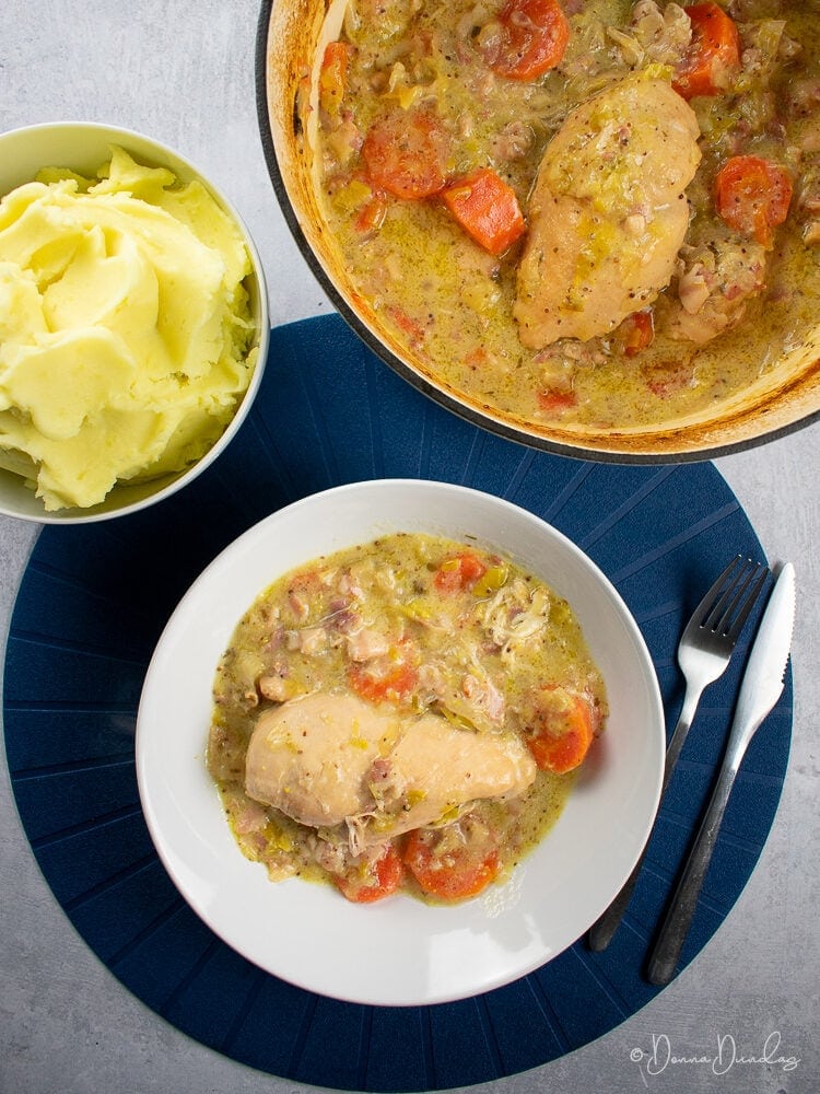 Top view of served portion of casserole, with cooking bowl and mashed potato to the side
