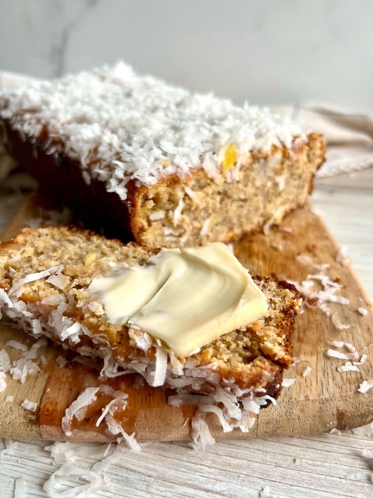 Piña Colada Banana Bread 1 Piña Colada Banana Bread on a cutting board with one slice laying down with butter pat on it