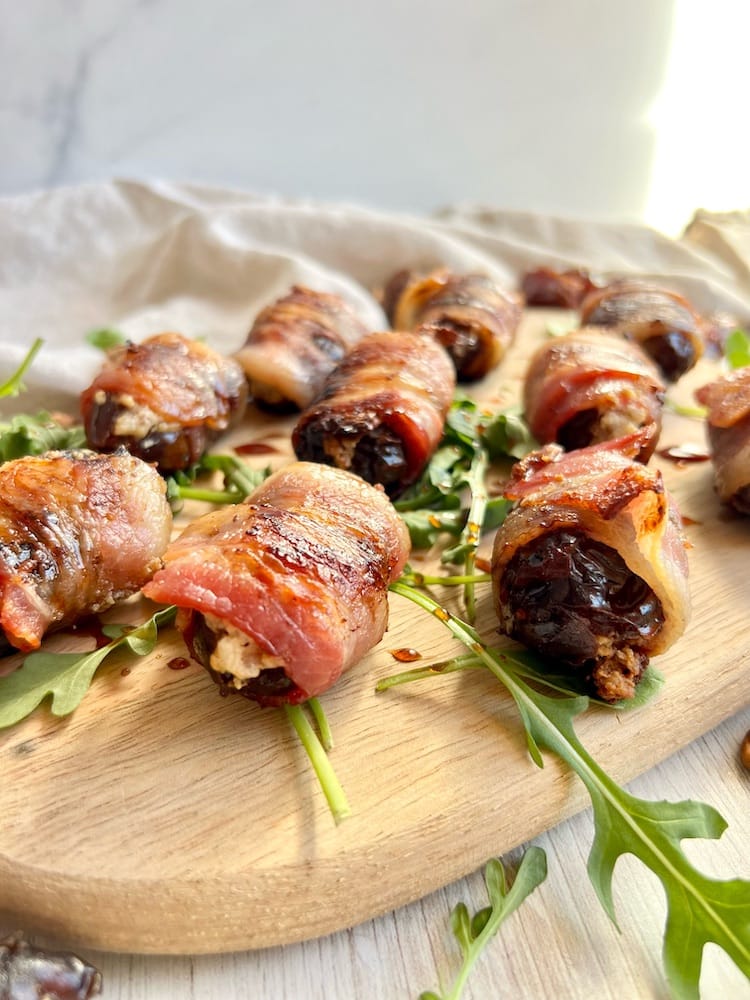 Bacon Wrapped Boursin Stuffed Dates Bacon Wrapped Boursin Stuffed Dates on a cutting board with arugula