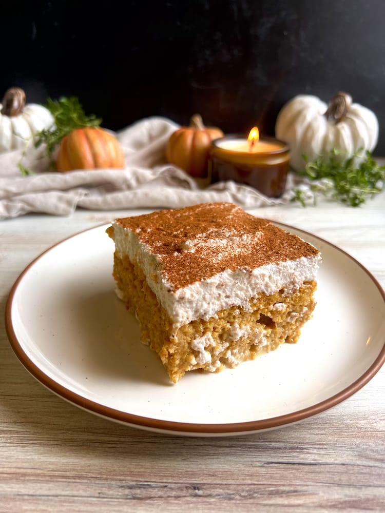 Pumpkin Tres Leches 1 A slice of Pumpkin Tres Leches on a plate with pumpkin decorations in the background