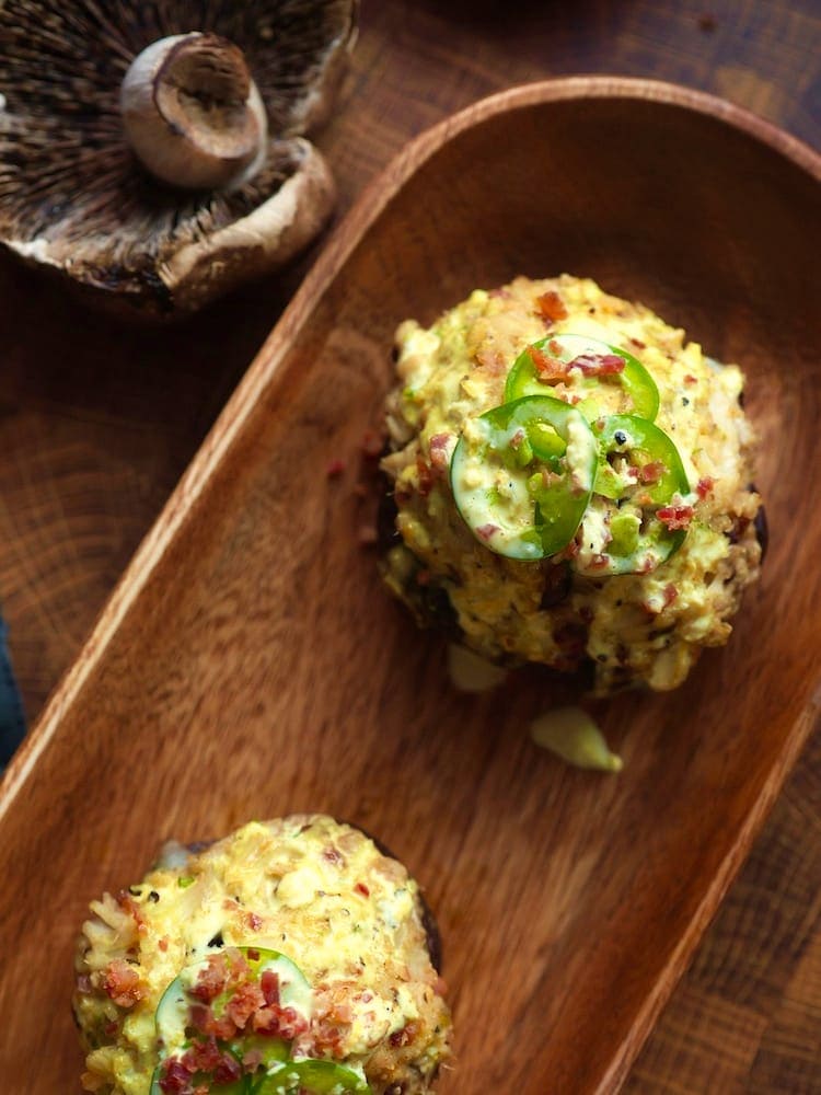 Crab Stuffed Portobello Mushrooms 6 WEB Crab Stuffed Portobello Mushrooms on a wooden serving platter with a fresh portobello in the upper left of the shot