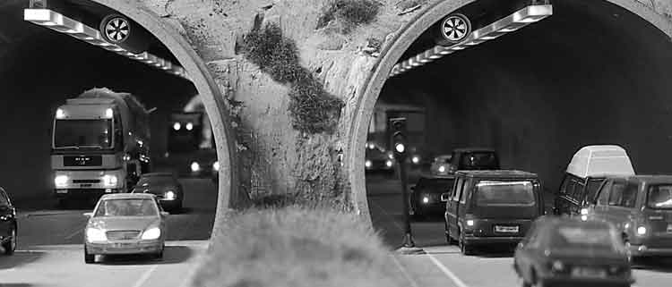 Das Bild zeigt einen Tunnel mit zwei Spuren, auf denen Fahrzeuge in den Tunnel und heraus fahren. Das Motto: In beide Richtungen gut sortiert. Dieses soll das Impressum der Seite beschreiben.