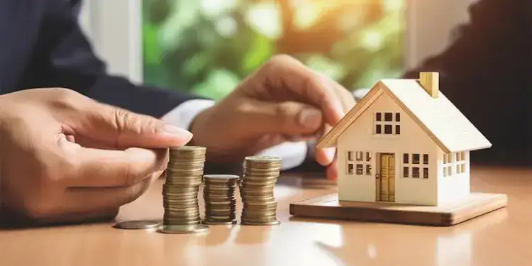 Stacked coins next to a toy house model symbolizing Nepal's home loan rates and housing finance options.