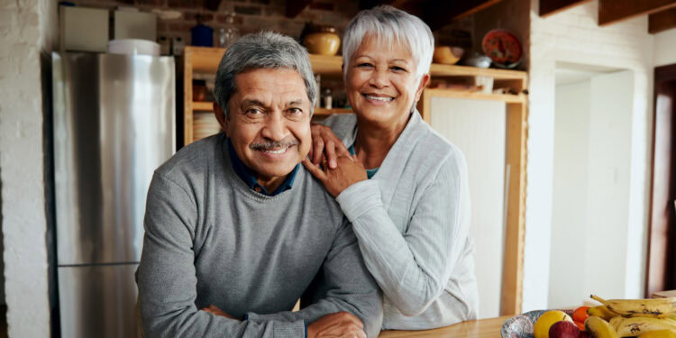Happy senior couple smiling in kitchen, healthy aging and mental well-being, positive psychology, senior health, elderly lifestyle, emotional well-being, age-friendly environment, healthy aging concepts, psy post psychology news.