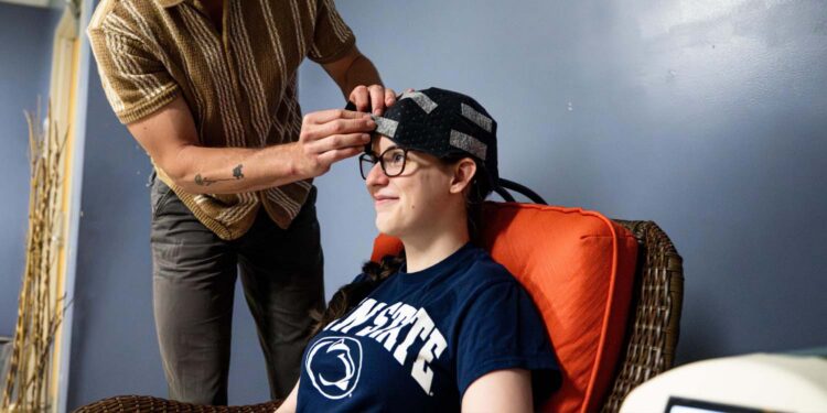 Co-authors Owen Griffith, standing, and Maddie McLaughlin demonstrate the head cooling cap used in the study. [Jaydyn Isiminger / Penn State]