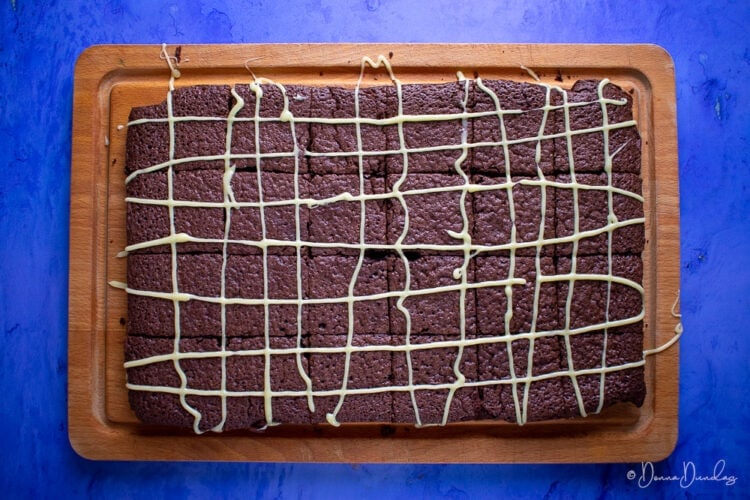 brownies on chopping board, blue background, shot from above.