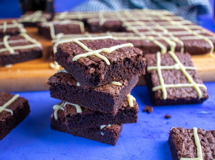 Stack of 4 brownies with tray of sliced squares in the background