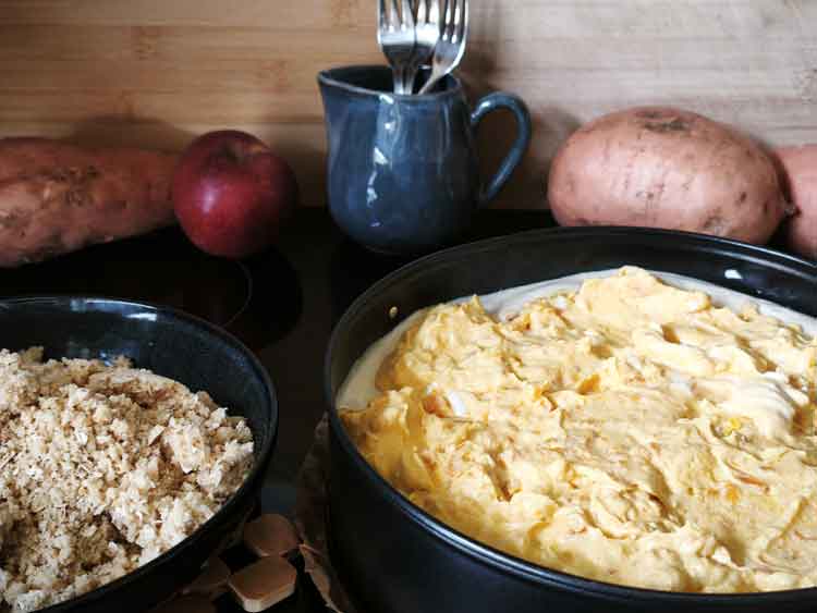 Der Pumpkin-Cheese-Pie besteht aus einem Keksboden, einer Quarkfüllung und einer getoppten Kürbis-Quark-Füllung. Die Streusel daneben müssen noch aufgestreut werden.