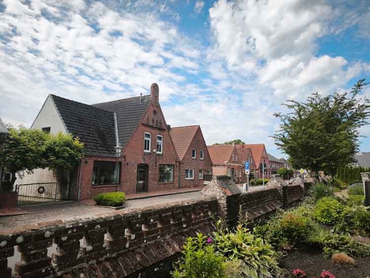 Die Oldensworter Fußgängerzone an der Kirche. Rote Backsteinhäuser stehen an einer Straße.