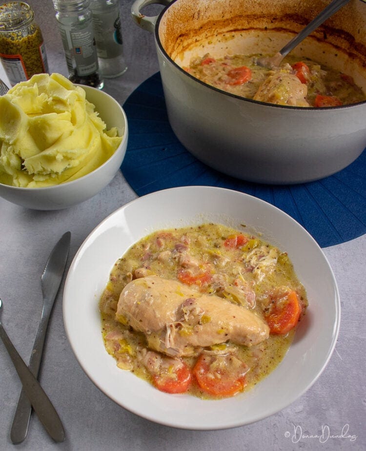 served portion of chicken casserole with cider in pasta dish, cast iron cooking dish, bowl of mashed potato and salt and pepper in background