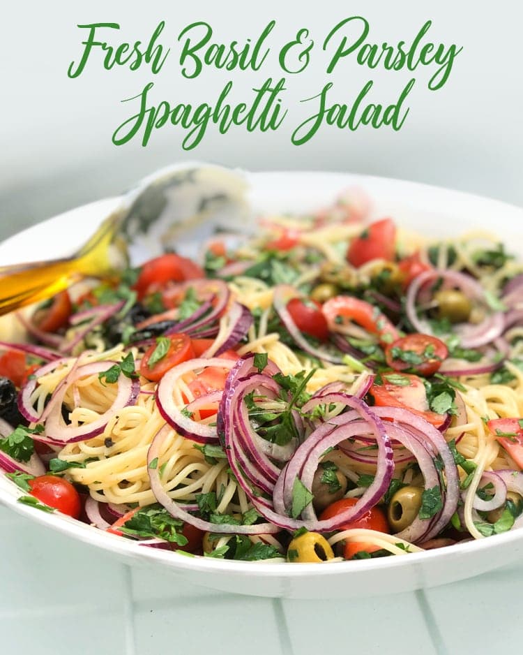 fresh basil and parsley spaghetti salad with raw onion, olives and tomatoes