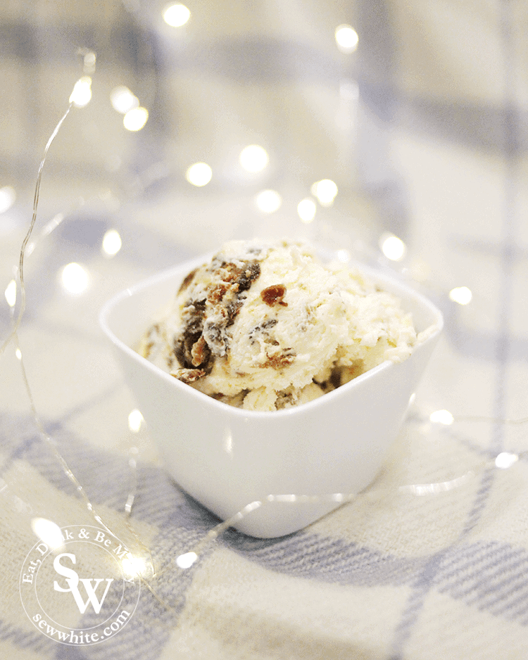 Easy Christmas Pudding Ice Cream using leftover christmas pudding. Scoops of the no churn ice cream in a bowl surrounded by fairy lights. 