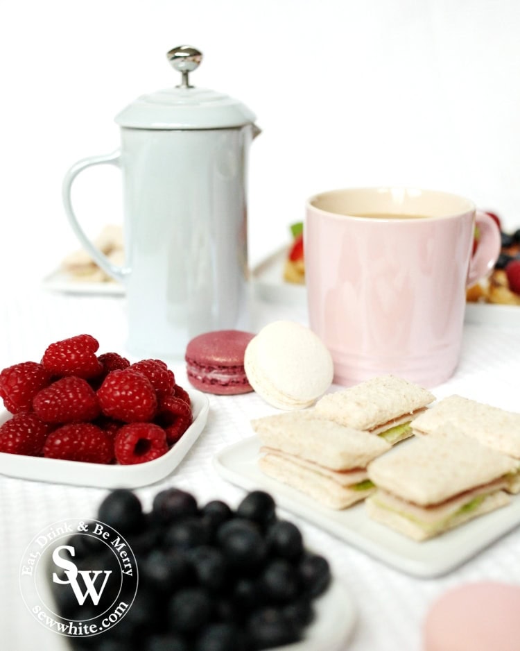 Stoneware cafetiere from Le Creuset galce collection along afternoon tea sandwiches, macarons and fruit