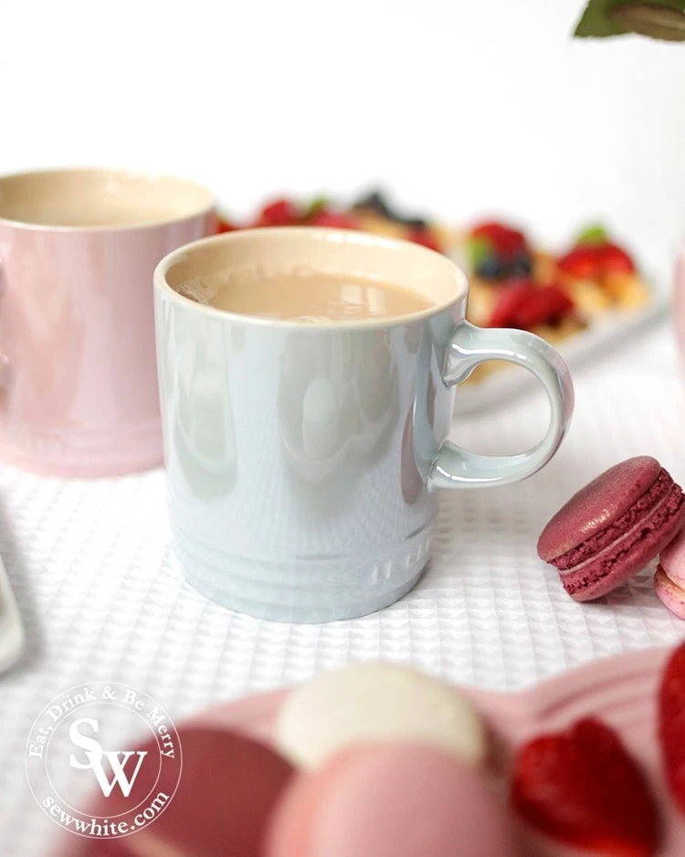 A cup of tea in the Le cureset stoneware glace collection mug served with macarons. 