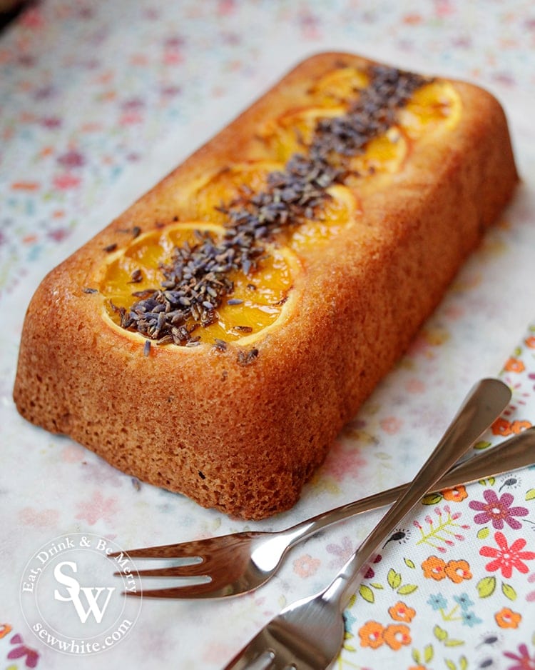 golden brown Orange Lavender Loaf ready to slice with silver dessert forks.