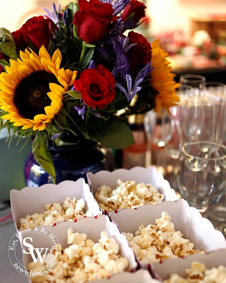 Sunflowers and roses in a dark blue vase with boxes of popcorn in front at the Beauty and the Beast Party.