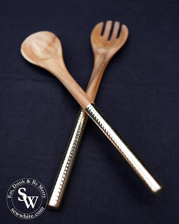 gold handled wood salad serves on a dark navy tablecloth. 