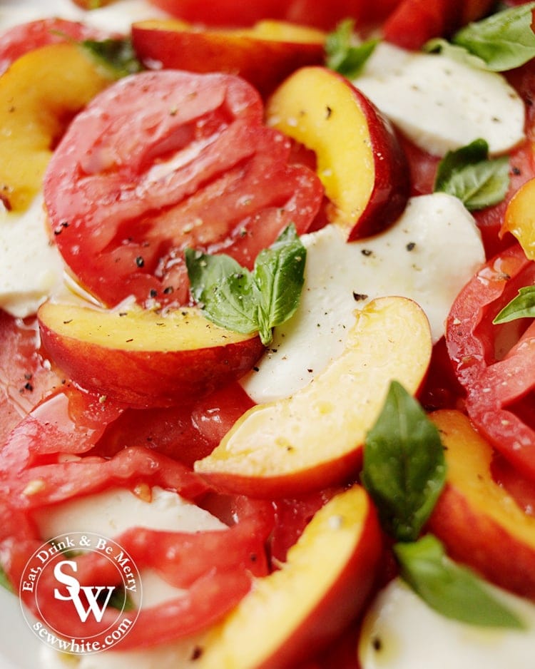 slices of red heirloom tomatoes in  a peach summer salad with mozzarella.