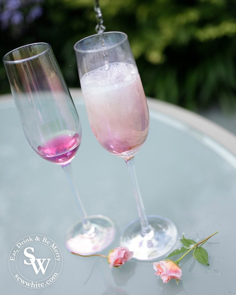 Pouring prosecco into the champagne glasses with elderflower and rose syrup for the Prosecco cocktail