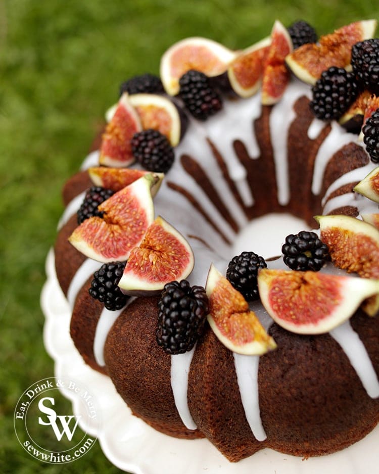 Autumn Cake topped with blackberries and figs on a cake plate