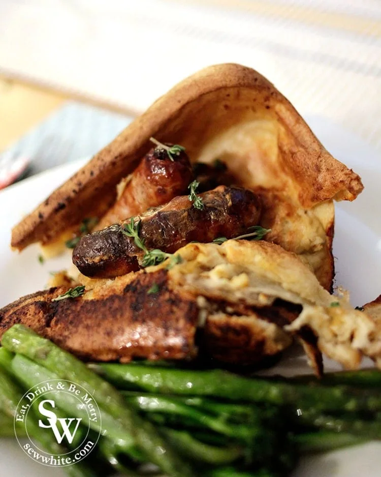 Golden brown toad in the hole topped with fresh thyme and served with vegetables.