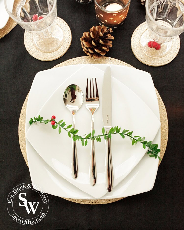 White plates tied with Christmas garland on the Black Gold and Red Christmas Table