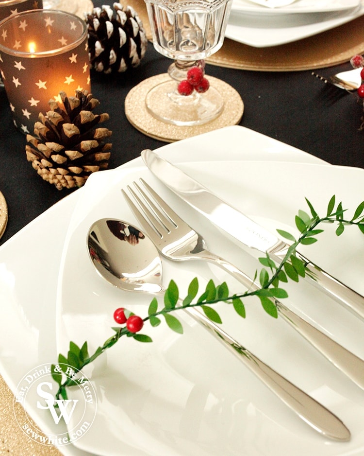 close up the Black Gold and Red Christmas Table setting with cutlery from Viners. Plates from marks and spencers, glasses from Sainsburys.