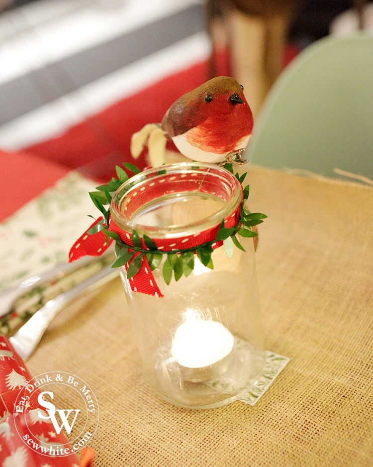 glass jar with red ribbon and a robin on for the Christmas table.