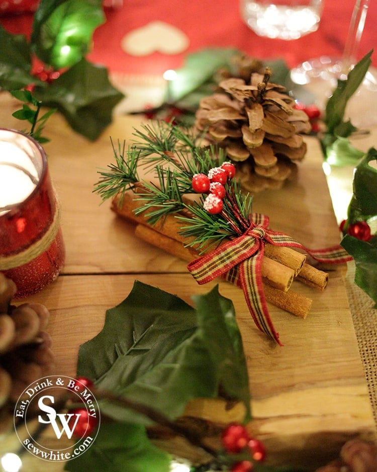 Finishing touches on the Red and Green Woodland Christmas Table with bundles of cinnamon sticks and pine cones.