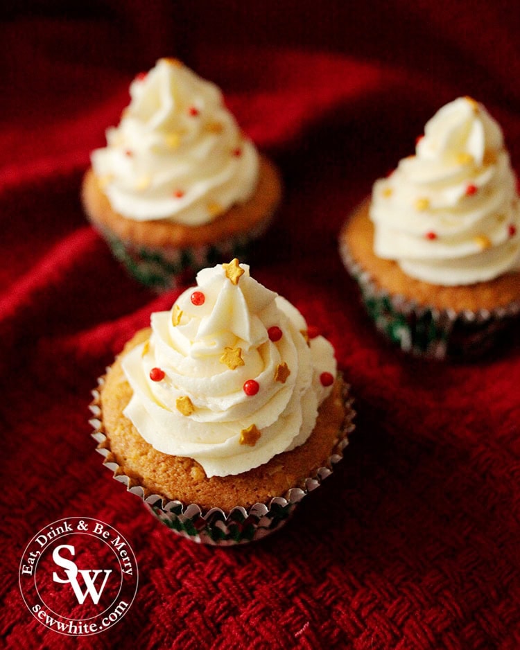 White Chocolate Christmas Cupcakes decorated with red sprinkles and gold stars looking like christmas trees.