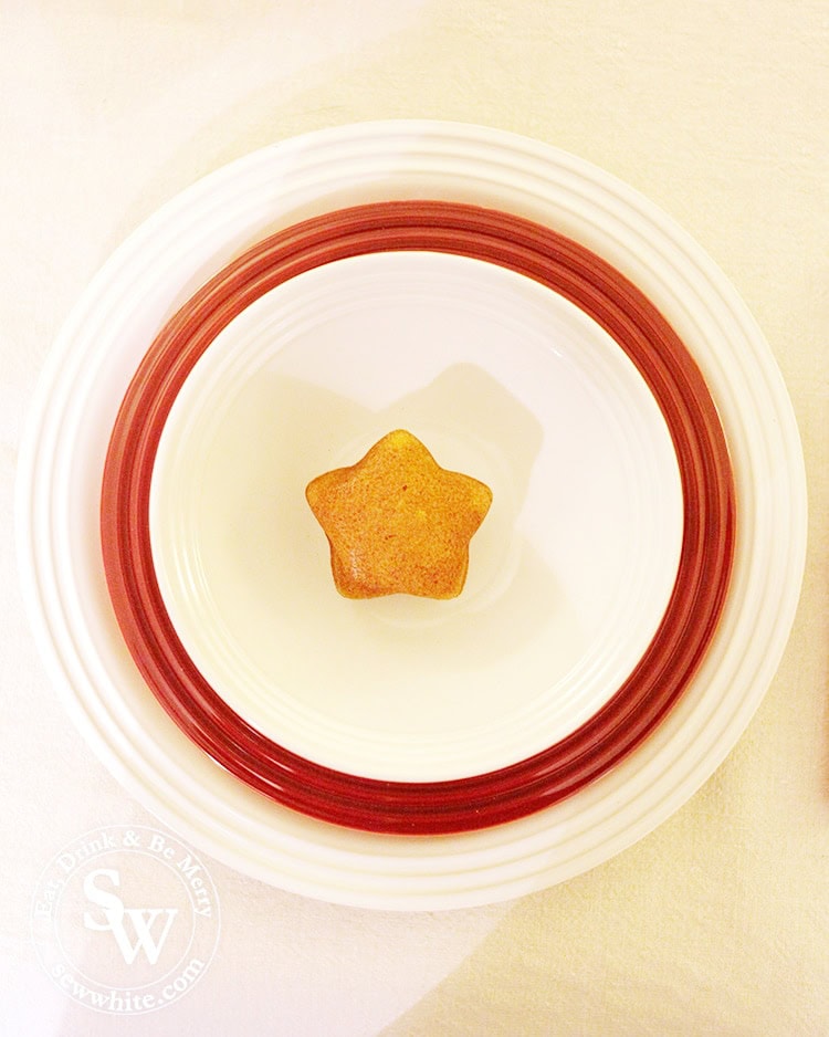 White and red plates stack with white bowl and star lemon cake as a Christmas place setting. 