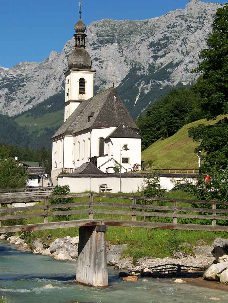 Die Kirche St. Sebastian in Ramsau vor dem Bergmassiv. Am Fuße plätschert der Wimbach.