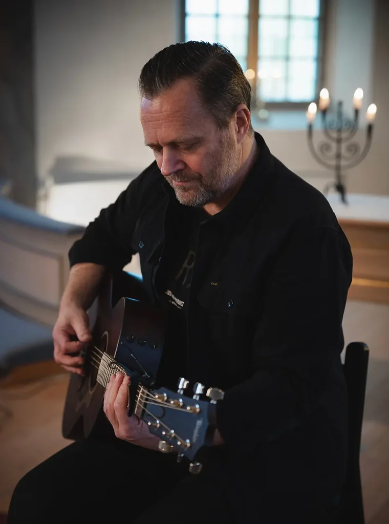 Porträtt på en man som spelar på akustisk gitarr