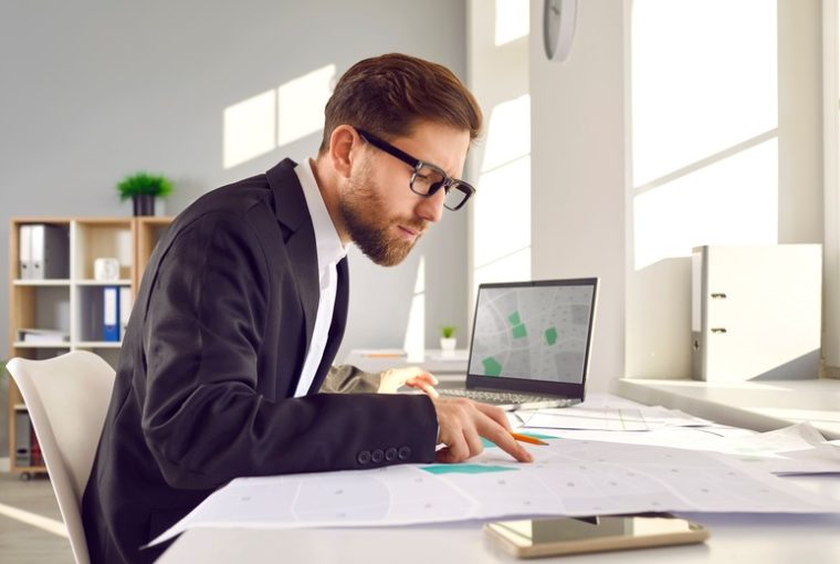 DOCFA, uomo a lavoro con documenti catastali e pc