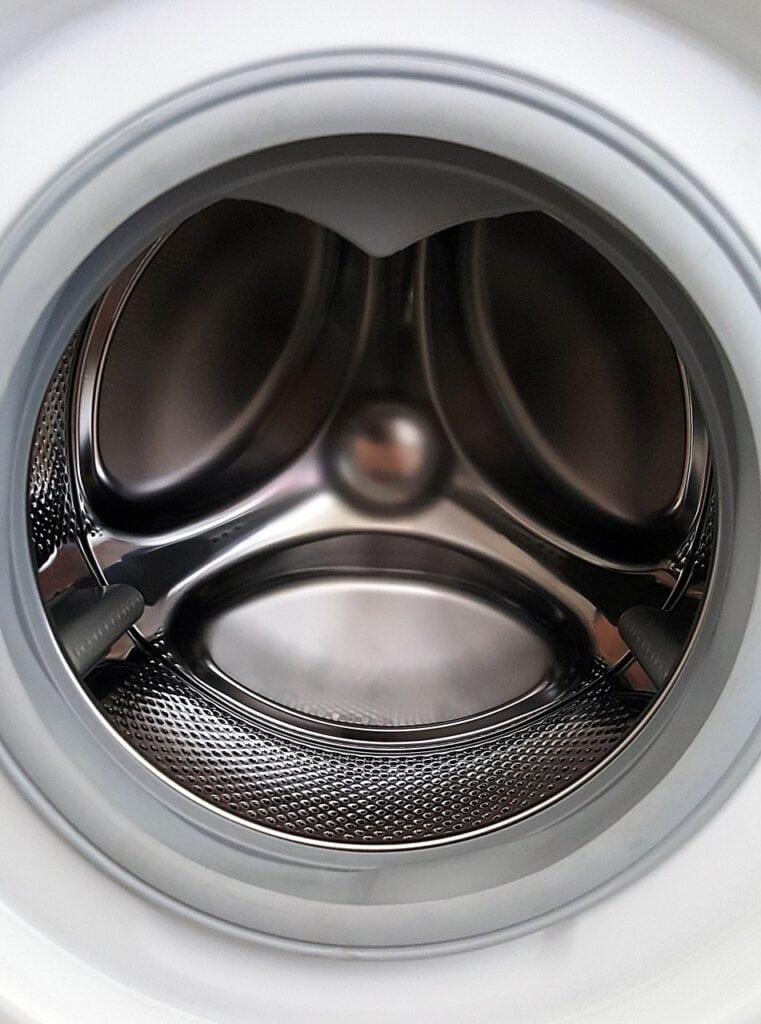Close up image of empty shining washing machine drum. Door open.