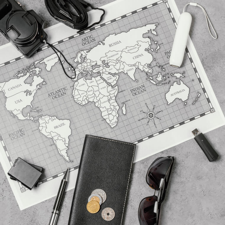 A world map surrounded by travel essentials like a camera, sunglasses, coins, and a passport.