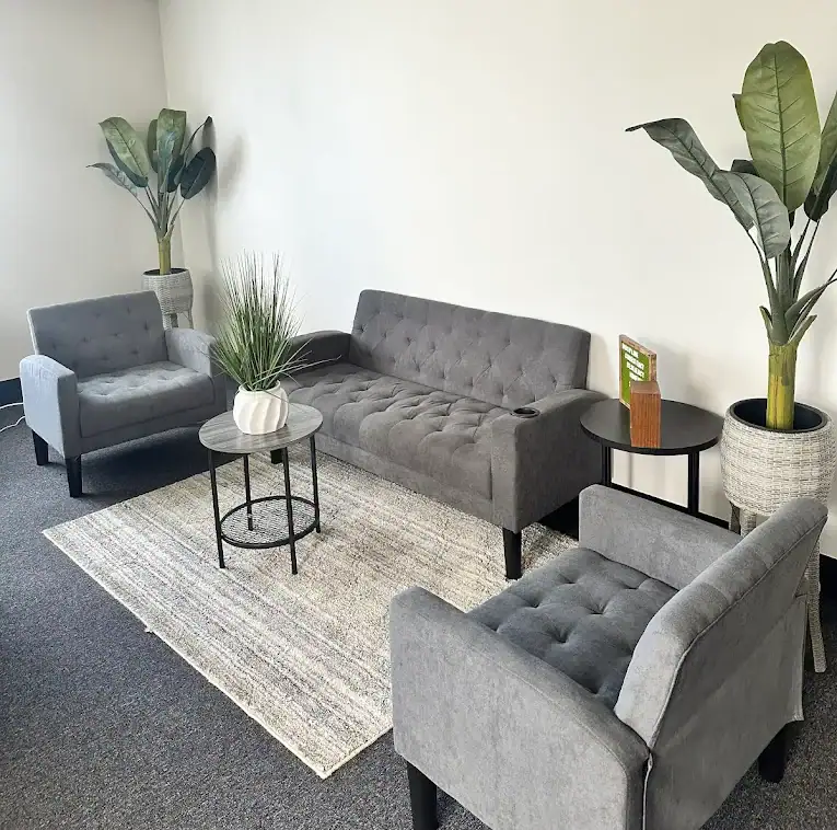 A waiting office with three sofas and two plants