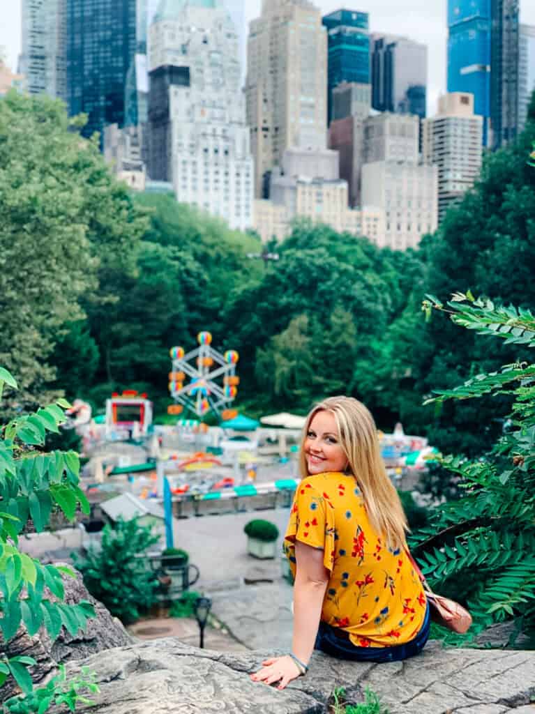 Young woman enjoying a city park with skyscrapers and a Ferris wheel in the background.