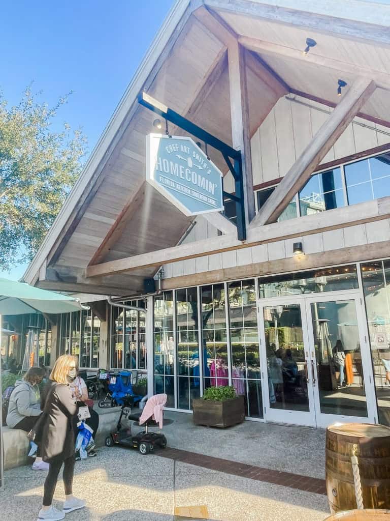 Cozy restaurant with large glass windows, outdoor seating, and people dining, located in a popular vacation area.