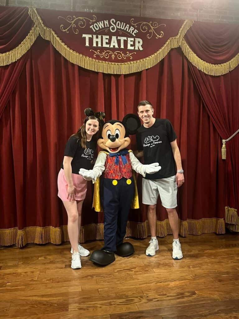 Mickey Mouse with visitors at Disney-themed event, family vacation photo.