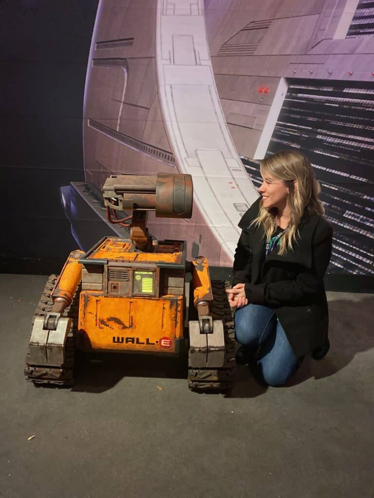 Woman with WALL-E robot model at SpaceX exhibit.