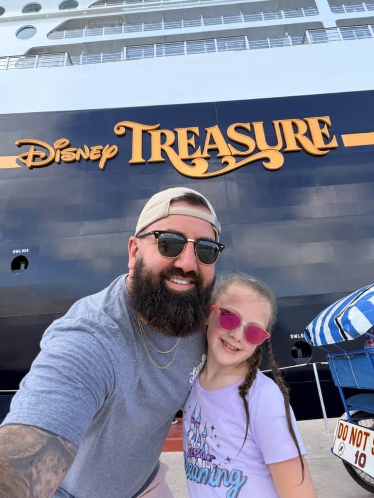 Family posing in front of Disney Treasure cruise ship.