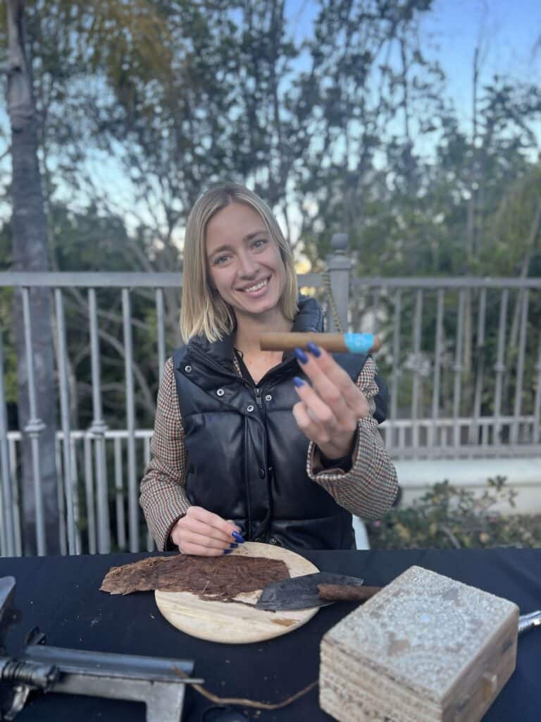 Female cigar roller holding a hand-rolled cigar at a Las Vegas event