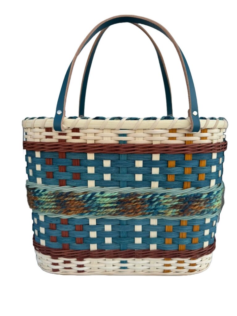 Blue tote bag with long dark handles and yarn and colored reed