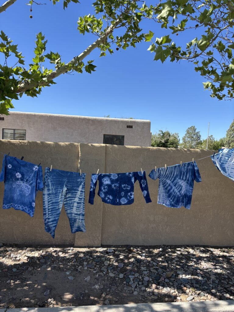 Indigo dyed clothing on clothesline in front of fence