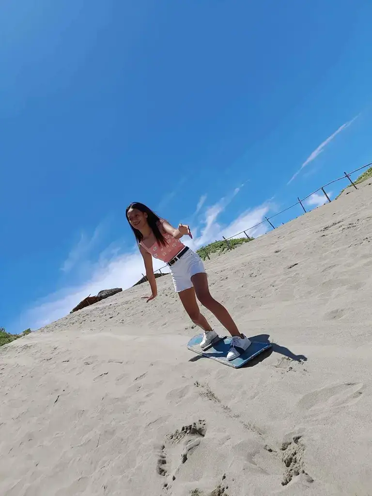 A picture of a young lady sandboarding in Paoay, Philippines.